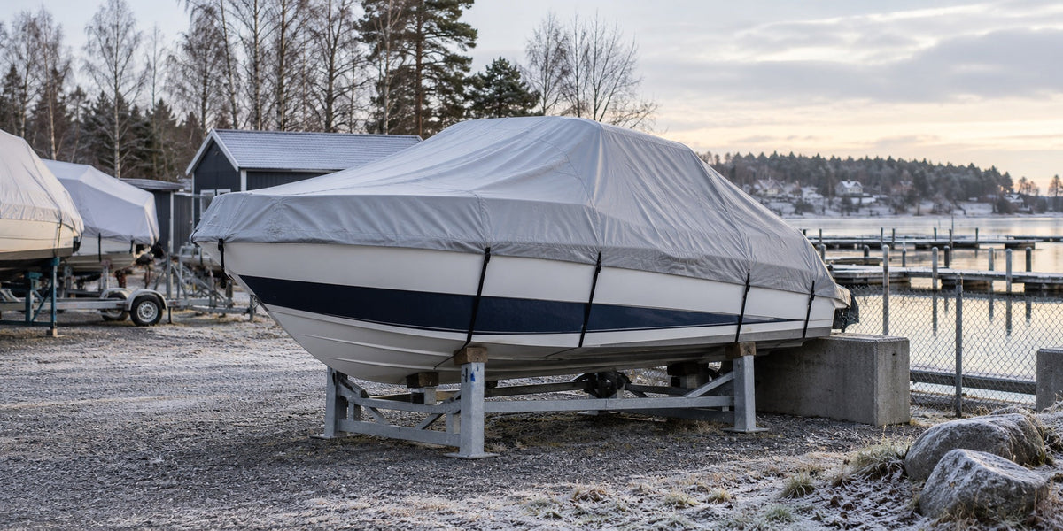 Täckt fritidsbåt på vagga vid en frostig marina under vinterförvaring